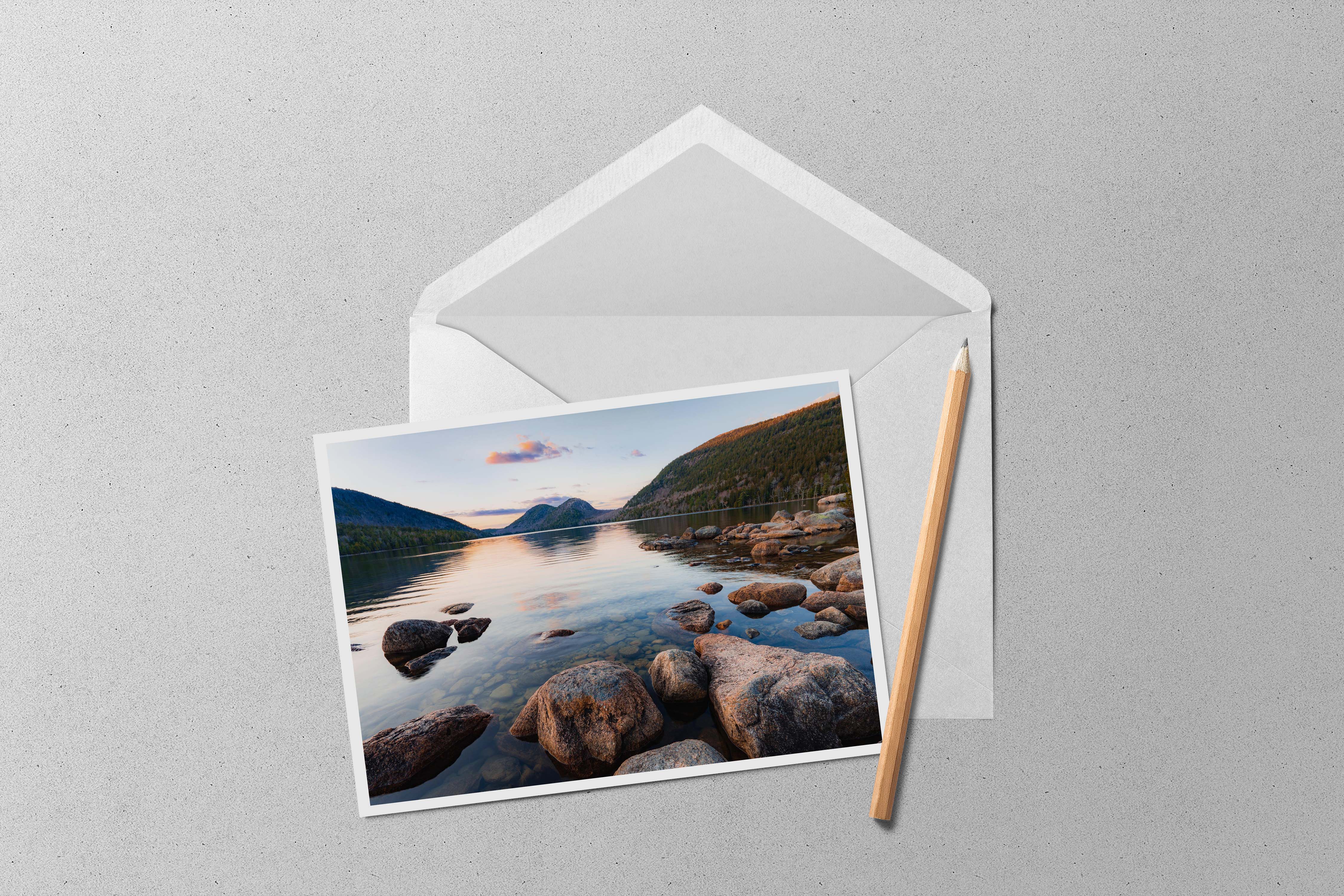 A photo of the mountains of Acadia National Park rising above the calm waters of Jordan Pond at sunset.